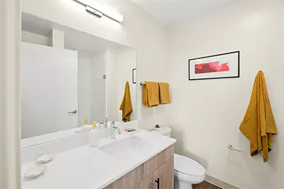 Modern apartment bathroom featuring a glass-enclosed shower, large vanity mirror, and bright lighting
